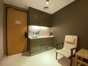 a bathroom with a sink and a chair next to a door at The Honeymoon Haven - 99 Residences in Melaka