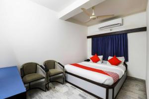 1 dormitorio con 1 cama, escritorio y sillas en OYO Flagship Hotel Capital, en Rajkot