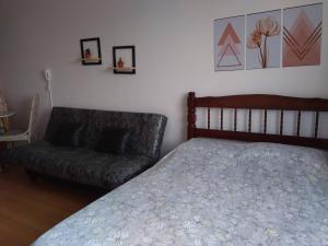 a bedroom with a bed and a couch at Lindo Studio na Praia do Gonzaguinha II in São Vicente