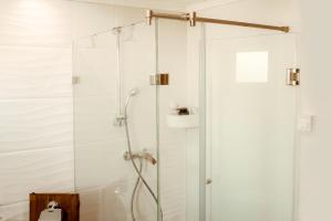 y baño con ducha y puerta de cristal. en Beneháti kunyhók en Matrafured