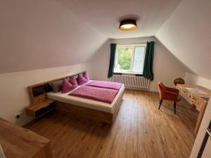 Un dormitorio con una cama con almohadas rosas y una ventana en HAR(z)MONIE Penthouse in Blankenburg, en Blankenburg