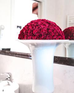 Hotel Isola Di Caprera في ميرا: مزهرية بيضاء مليئة بالورود الحمراء في الحمام