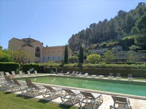 a pool with chairs and a building in the background at Hôtellerie Notre Dame de Lumières in Goult