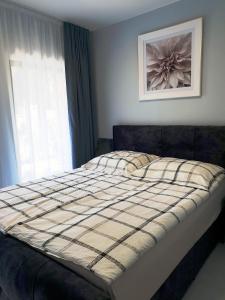 a bed in a bedroom with a window and a picture at Apartamenty Kornel 3 in Pobierowo