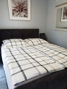 a bed with a checkered blanket on top of it at Apartamenty Kornel 3 in Pobierowo
