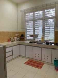 cocina con armarios blancos, fregadero y ventana en Magnolia homestay 2 
