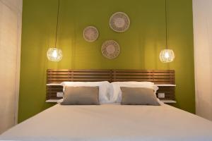 a bedroom with a large white bed with green walls at Sunrise Sardinia Posada in Posada