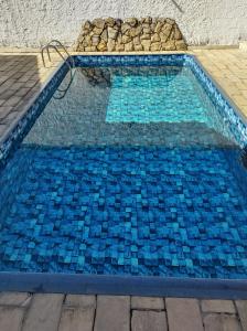 een zwembad met blauwe tegels op de vloer bij Chácara Bom Jesus in Aparecida
