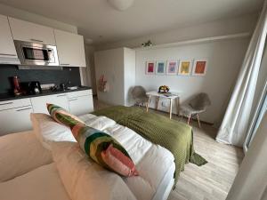 a bedroom with a bed with pillows and a kitchen at Komfortables, barrierefreies Appartement mit sonnigem Balkon in der Nähe von Flughafen und Messe 30 in Leinfelden-Echterdingen