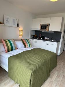 a bedroom with a bed with a green blanket on it at Komfortables, barrierefreies Appartement mit sonnigem Balkon in der Nähe von Flughafen und Messe 30 in Leinfelden-Echterdingen