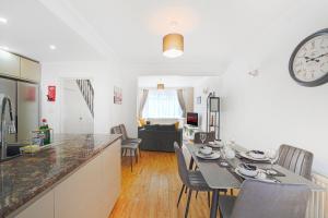 a kitchen and living room with a table and a clock at Special Offers, Sleeps 5, Hanwell, London W7, Free Parking in Greenford