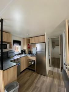 a kitchen with wooden cabinets and a stainless steel refrigerator at Mobil-home Les Dunes de Contis in Saint-Julien-en-Born +3 photos