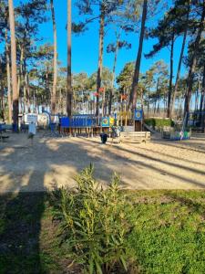 un parque con parque infantil con bancos y árboles en Mobil-home Les Dunes de Contis, en Saint-Julien-en-Born