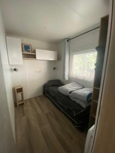 Cette petite chambre comprend 2 lits et une fenêtre. dans l'établissement Mobil-home Les Dunes de Contis, à Saint-Julien-en-Born