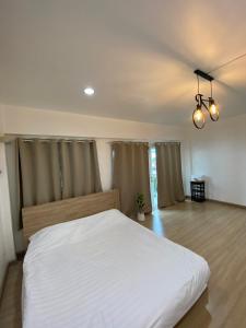 um quarto com uma grande cama branca num quarto em Thanyaporn Guest House - Don Mueang em Thung Si Kan
