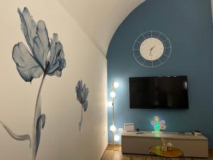 a living room with a clock on the wall and a table at Dimora Nonno Ciccio in Polignano a Mare