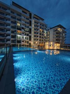- une piscine en face de certains bâtiments la nuit dans l'établissement EzyGo Homestay Kuching - P'Residence, à Kuching
