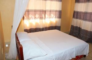 ムトワッパにあるFLORENCE APARTMENTS Bのカーテン付きの客室の小さなベッド1台分です。