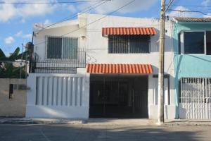 a white building with a gate and a garage at Casa Calis Cancún in Cancún