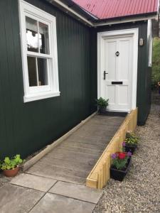 Casa verde con porche de madera y puerta blanca en Wee House in beautiful surroundings Maybole, en Maybole
