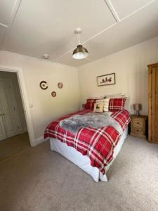 1 dormitorio con 1 cama con manta de cuadros roja en Wee House in beautiful surroundings Maybole, en Maybole