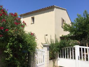 a white fence in front of a house with roses at Gite Du Lavoir in Saint-Geniès-de-Comolas