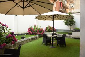 un patio avec deux tables, des chaises et deux parasols dans l'établissement Hotel Valentino Du Parc, à Turin