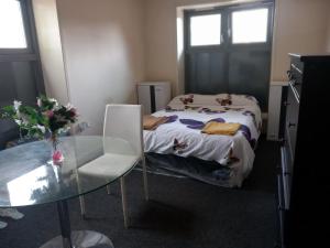 een kleine kamer met een bed en een glazen tafel bij Jah lodge in Croydon