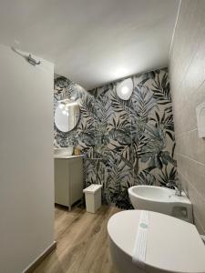 a bathroom with a toilet and two sinks and a leafy wallpaper at Dimora Nonno Ciccio in Polignano a Mare