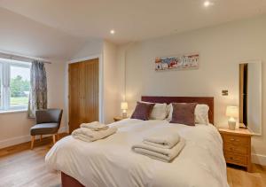 a bedroom with a large bed with towels on it at Roosters Rest in Beccles