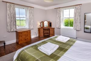 a bedroom with a large bed with a mirror and windows at The Old Farmhouse at Roughs Farm Retreats in Huntingdon