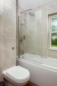 a bathroom with a tub and a toilet and a shower at The Old Farmhouse at Roughs Farm Retreats in Huntingdon