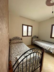 a bedroom with two beds and two windows at Appartement à louer Al Hoceima - Mirador in Al Hoceïma +10 photos