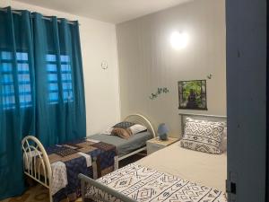 two beds in a room with blue curtains at La maison de la plage in Sainte-Luce