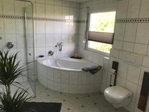 a white bathroom with a tub and a toilet at Ferienwohnung Im Grünen in Schramberg
