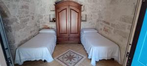 two twin beds in a room with a wooden cabinet at Trulli Vāyu in Villa Castelli