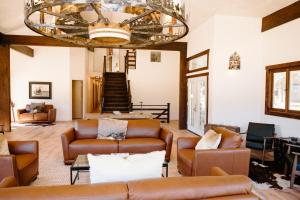 a living room with leather couches and a chandelier at The Lodge at Silver Ridge Ranch in Cabin Creek