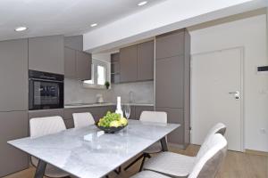 a kitchen with a table and white chairs at Luxury Apartments Luna in Tučepi