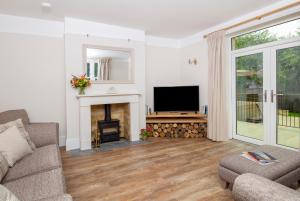 sala de estar con chimenea y TV en The Old Farmhouse at Roughs Farm Retreats, en Huntingdon