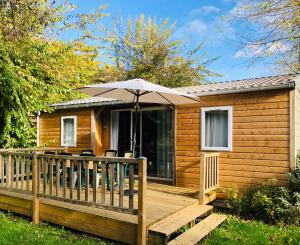 a cabin with an umbrella on a wooden deck at Camping la Venise Verte in Coulon