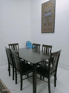 een zwarte tafel met vier stoelen en een foto aan de muur bij Homestay Triple Q Manjung in Seri Manjung