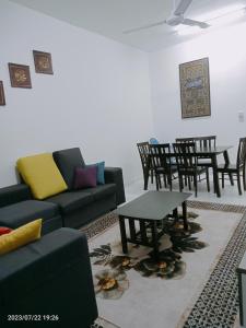 een woonkamer met een bank en een tafel en stoelen bij Homestay Triple Q Manjung in Seri Manjung