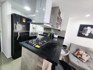 メデジンにあるApartamento con Parqueadero y Vista a la Ciudadのキッチン(黒いカウンタートップ、冷蔵庫付)