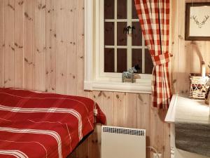 a bedroom with wooden walls and a window with a red blanket at Holiday home Engerdal 