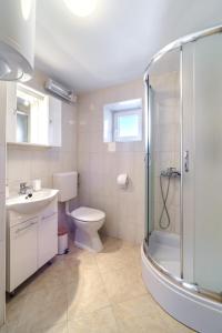 uma casa de banho com um chuveiro, um WC e um lavatório. em Apartmani P&S em Supetar