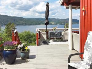 an outdoor deck with an umbrella and flowers on a house at Holiday home Klokkarstua in Svelvik