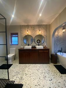 La salle de bains est pourvue de 2 lavabos, d'une baignoire et de miroirs. dans l'établissement Dolphin Circle Bed and Breakfast, à Plettenberg Bay