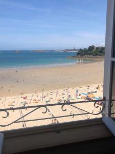 a view of a beach from a window at Le Royal XIX Dinard vue mer luxe in Dinard