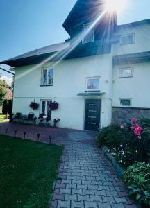 a white house with the sun shining on it at Dom Gościnny Kama in Tylicz