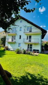 a large white building with balconies and a yard at Dom Gościnny Kama in Tylicz